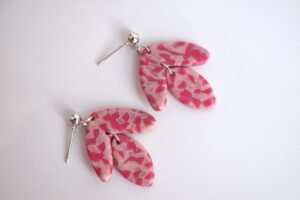 Pendientes artesanales con arco invertido y óvalo colgante, hechos a mano con arcilla polimérica en tonos rosa oscuro, rosa perla y ocre rosado, con enganche de bola plateada.